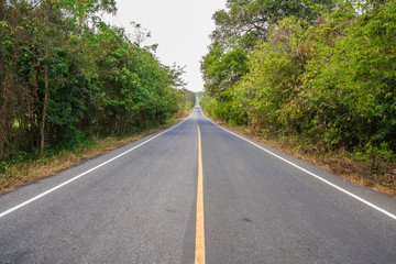 Fototapeta na wymiar Long macadamized road ahead with trees and sky clouds : countryside Thailand