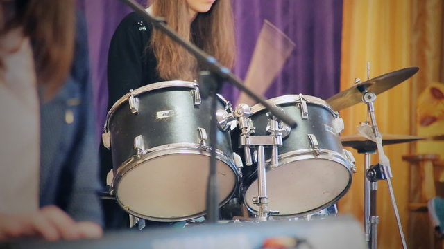 Students, boys and girl, teens  at a school concert. The girl - drummer
