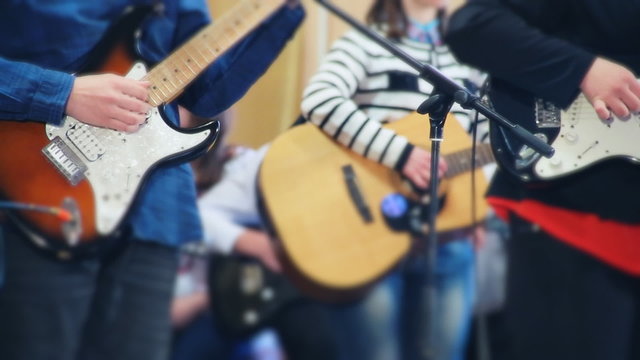 Students teens guitarists in the school concert with an acoustic and electric guitars