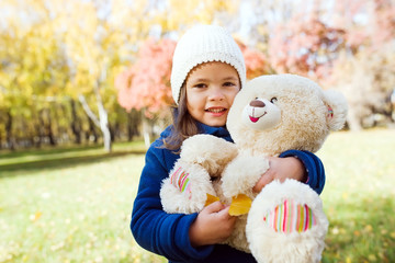 Little cute girl holding large teddy bear