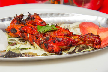 roasted chicken leg piece with salad served in plate at a restau