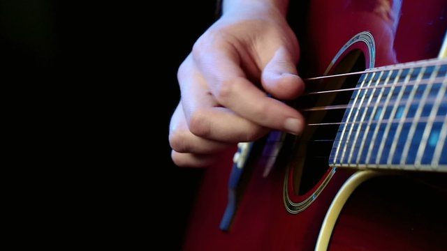 Man playing an acoustic guitar. The right hand close-up. Pluck the strings. Copyspace on the left.