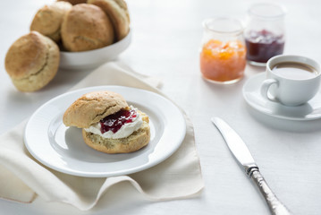 Scones with cream and fruit jam and cup of coffee