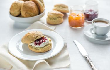 Scones with cream and fruit jam and cup of coffee