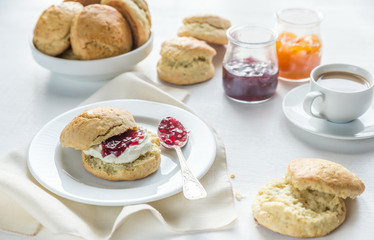 Scones with cream and fruit jam and cup of coffee