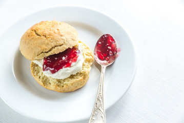 Scone with cream and cherry jam on the plate