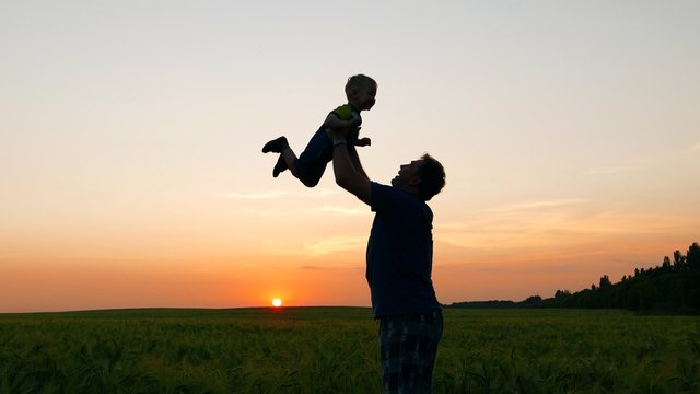 happy family, loving father picks up in hands and amuse kid baby at sunset. Childhood dreams and memories.