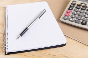 Blank white notebook with pen on wood desk. shallow depth of field