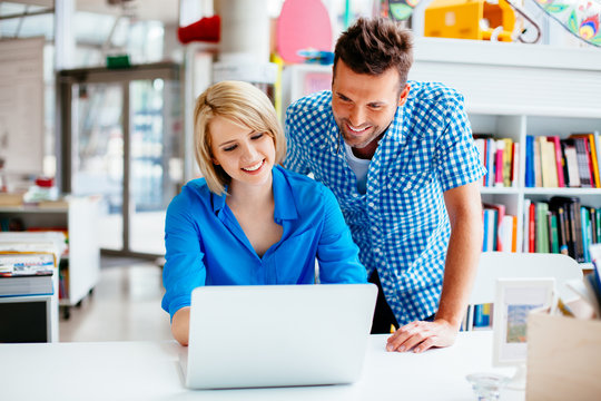Happy student and teacher learning in library on laptop computer