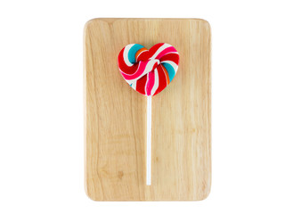 Heart shaped colorful lollipop on wooden tray, white background
