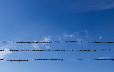 Barbed wire and blue sky with clouds