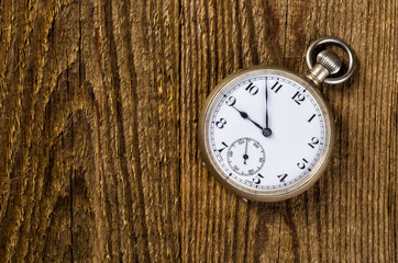 Old pocket watch and key on the wooden background with blank spa