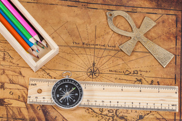 Fototapeta na wymiar Old style brass compass and color pencil on antique map