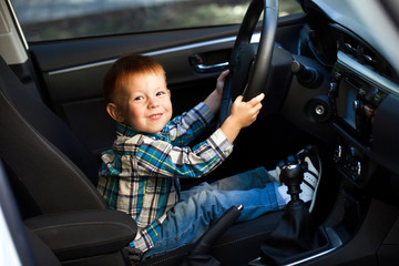 Cute little boy driving fathers car