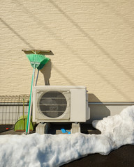 Heat pump unit on the side of a home in winter.