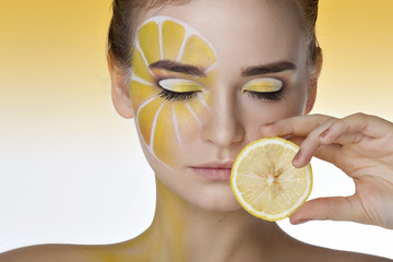 Beautiful young woman portrait with lemon and bright creative yellow makeup