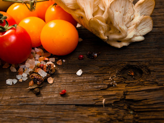 Fresh vegetables on a textured wooden table with sunlight. Tomatoes and red cabbage with herbs,salt and other vegetables. Space for titles and text. Close-up.