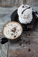 Hot coffee with marshmallows in a cup on the wooden background