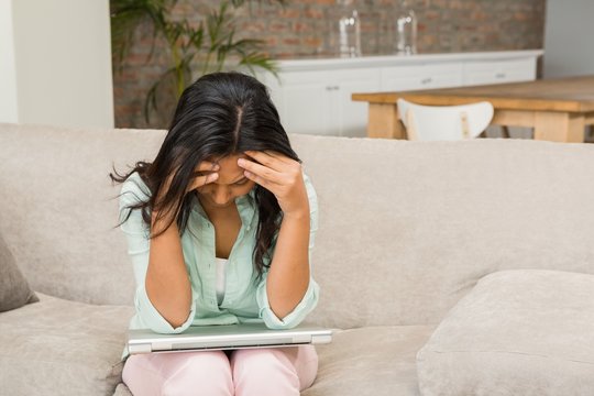 Worried Brunette With Closed Laptop On Her Legs