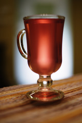 Two glasses with cherry compote, cherries on a plate, napkin on a pink wooden background. 
