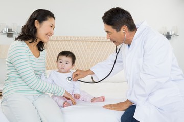 Fototapeta premium Cute baby being visited by doctor