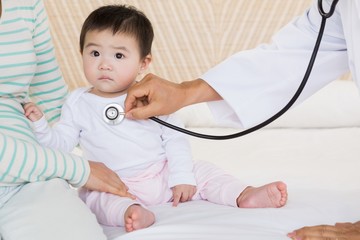 Cute baby being visited by doctor