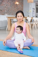 Serious woman sitting on mat with baby daughter
