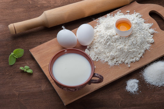Flour , eggs and milk on dark wooden background. Top view