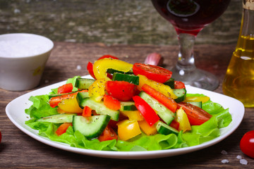 Helpful Fresh Salad of cucumbers, tomatoes, pepper and lettuce dressed with olive oil.