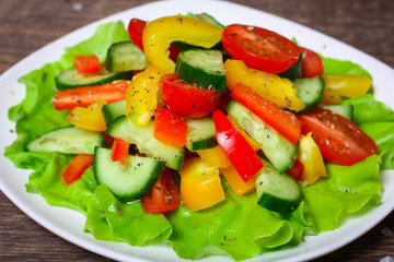 Helpful Fresh Salad of cucumbers, tomatoes, pepper and lettuce dressed with olive oil.