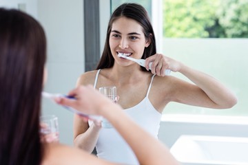 Smiling brunette brushing teeth