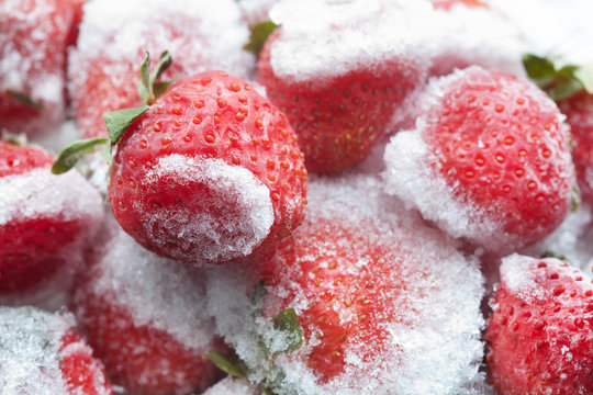 Frozen strawberries with green leaves closeup. Detailed cold fruit image. soft focus