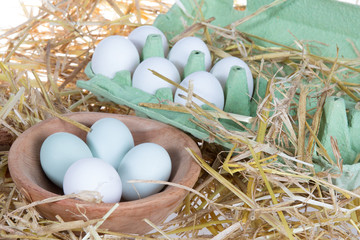 Green and a white eggs in wooden square bowl