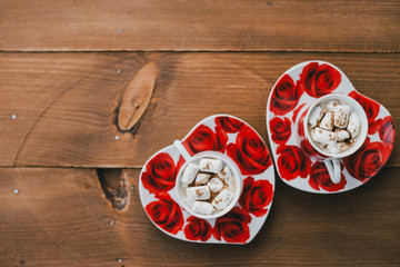 Two cups of hot cocoa with marshmallows and cinnamon on wooden background. Valentine's Day