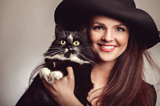 Beautiful woman in black dress and hat with cat 