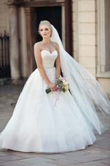 Beautiful fairytale blonde bride posing with bouquet in old ital