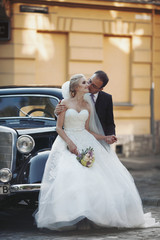 Naklejka premium Happy newlywed couple, man and wife kissing near stylish retro c