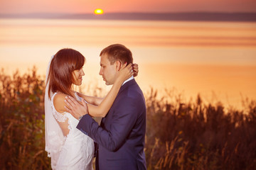 Beautiful happy couple is embracing at golden summer sea sunset