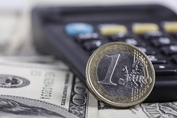 coin euro closeup, calculator on the background of banknotes dollars