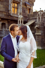 Portrait of beautiful wedding couple kissing near castle