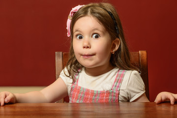 Expressive beautiful little girl playing indoor, face gesturing, miming, acting. Girl with astonished expression