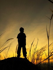 silhouette of boy on rock at sunsrise
