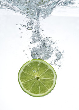 Lime dropped in a water on white background