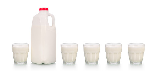 Five glasses of milk by plastic bottle on white