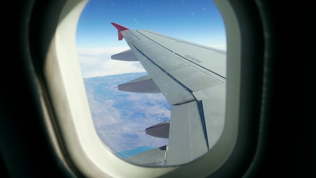 Aerial survey. Tourist flight of aircraft. Plane flies over the mountains. View from the window of the plane with a wing