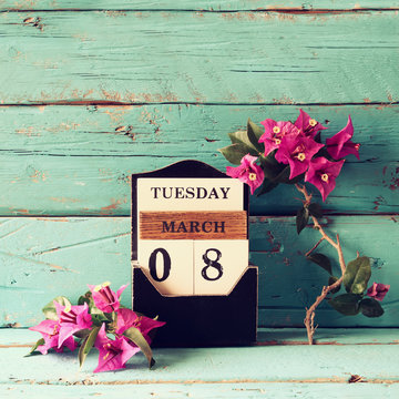 wooden March 8 calendar, next to purple flowers on old blue rustic table. selective focus. vintage filtered
