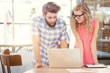 Composite image of a man using a laptop while discussing with a woman 