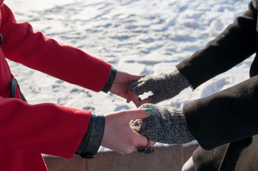 Young couple holding hands standing outdoors in winter, closeup
