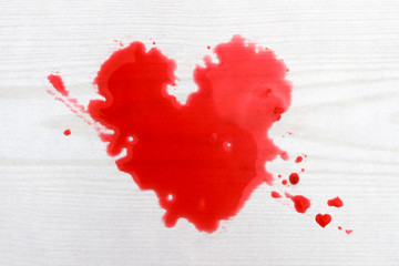 Heart shaped drops of red juice against wooden background