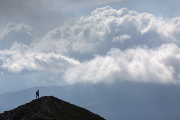 Silhouette of climbing young adult at the top of summit with aer